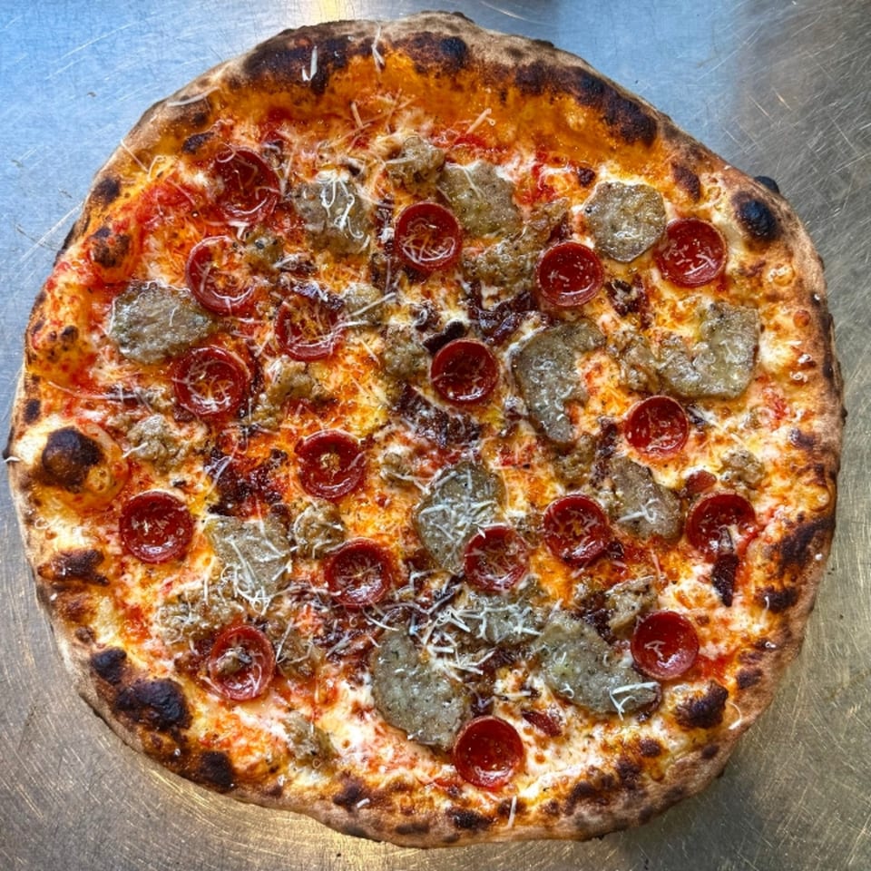 A whole pepperoni and sausage pizza with a crispy crust, topped with melted cheese and sauce.